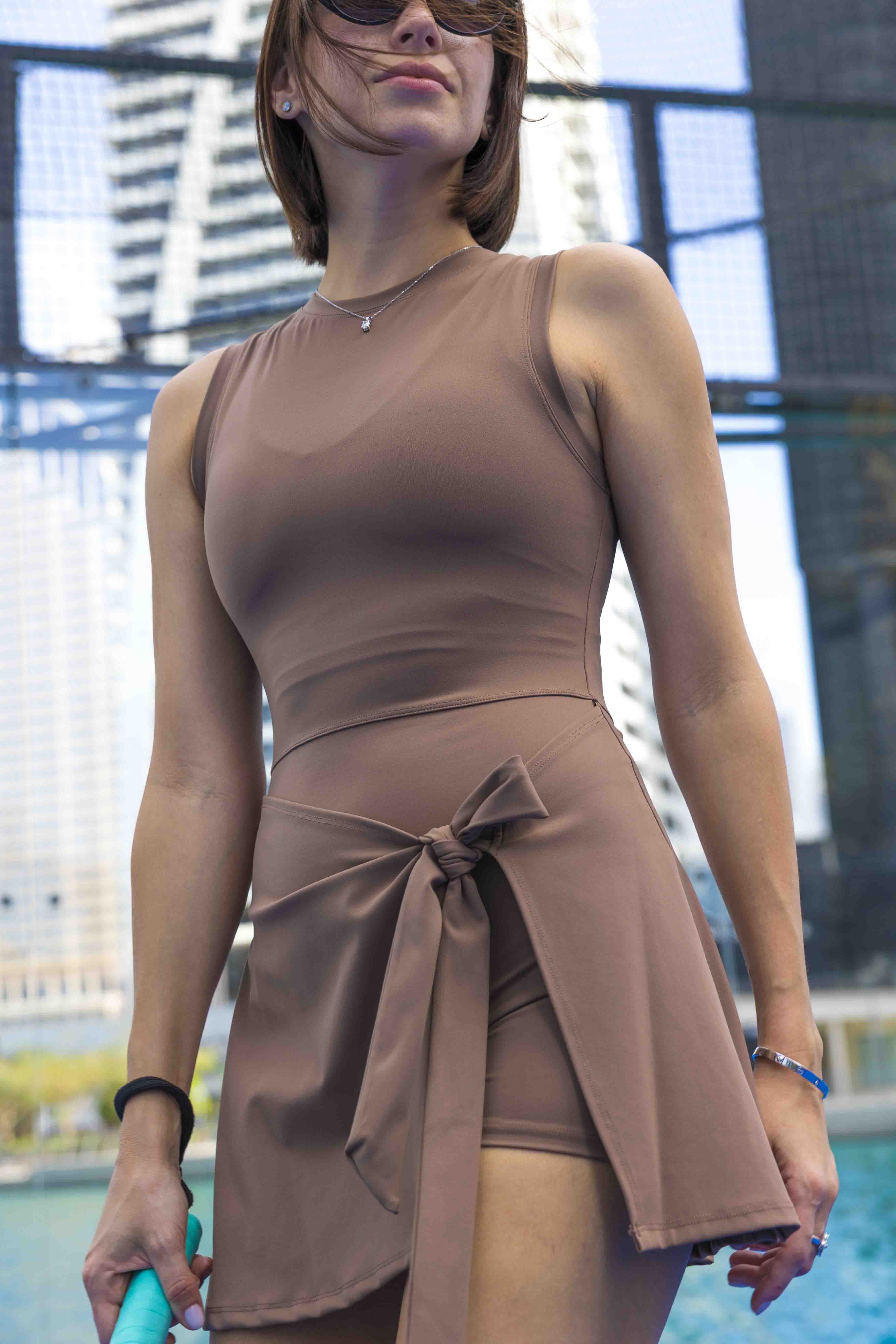SVL Padel Play & Party Dress in mocha brown, featuring a chic wrap-tie detail, flattering silhouette, and built-in shorts for versatile wear on and off the padel court
