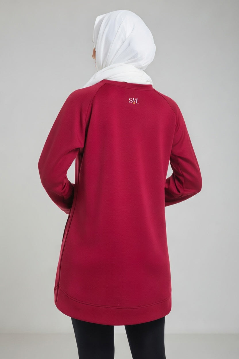 Rear view of a female player wearing a maroon SVL modest padel tunic, showing the embroidered logo on the upper back and a white hijab.