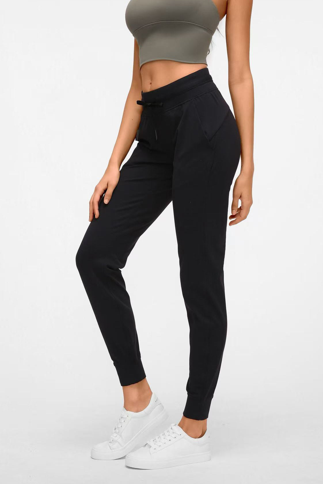 Side profile view of the black Arwa sweatpants highlighting the functional side pocket and streamlined performance silhouette.