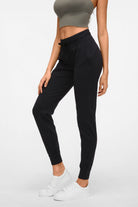 Side profile view of the black Arwa sweatpants highlighting the functional side pocket and streamlined performance silhouette.