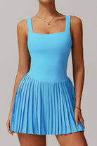 Front studio shot of the cyan blue Daria performance tennis and padel dress, featuring a modern square neckline and a sharp pleated skirt.