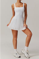 A full-length studio pose of the white Daria pleated tennis and padel dress highlighting its airy, modest athletic silhouette.