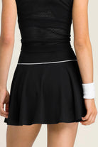 Rear view of the black SVL Kate padel and tennis skirt paired with a black mesh-back top, showing the athletic fit.