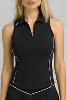 Front studio shot of the black SVL Kate performance tennis and padel top, featuring a sleeveless zip-up polo design with white piping details.