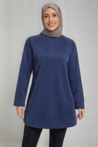 A female player wearing a modest navy blue SVL padel tunic with long sleeves and a taupe hijab, designed for athletic performance and coverage.