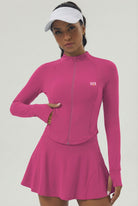 A female padel player wearing the dark pink Swan Sway jacket and a white visor, showcasing the athletic fit and integrated thumb holes.