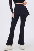 A front-angle studio shot of the black Tala flared performance leggings featuring an integrated asymmetrical wrap skirt overlay.