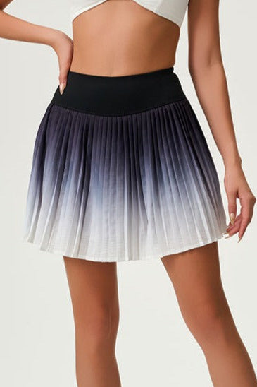 Close-up studio view of the SVL Valeria padel skirt featuring a black to white ombre gradient and sharp athletic pleats.