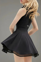 Rear profile view of the black Wiktoria padel and tennis dress showing the structured back and the flow of the mesh-trimmed athletic skirt.