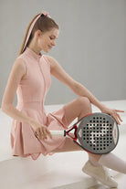 A seated action pose showing the pink Wiktoria padel dress, highlighting its comfortable performance fabric and stylish athletic design.