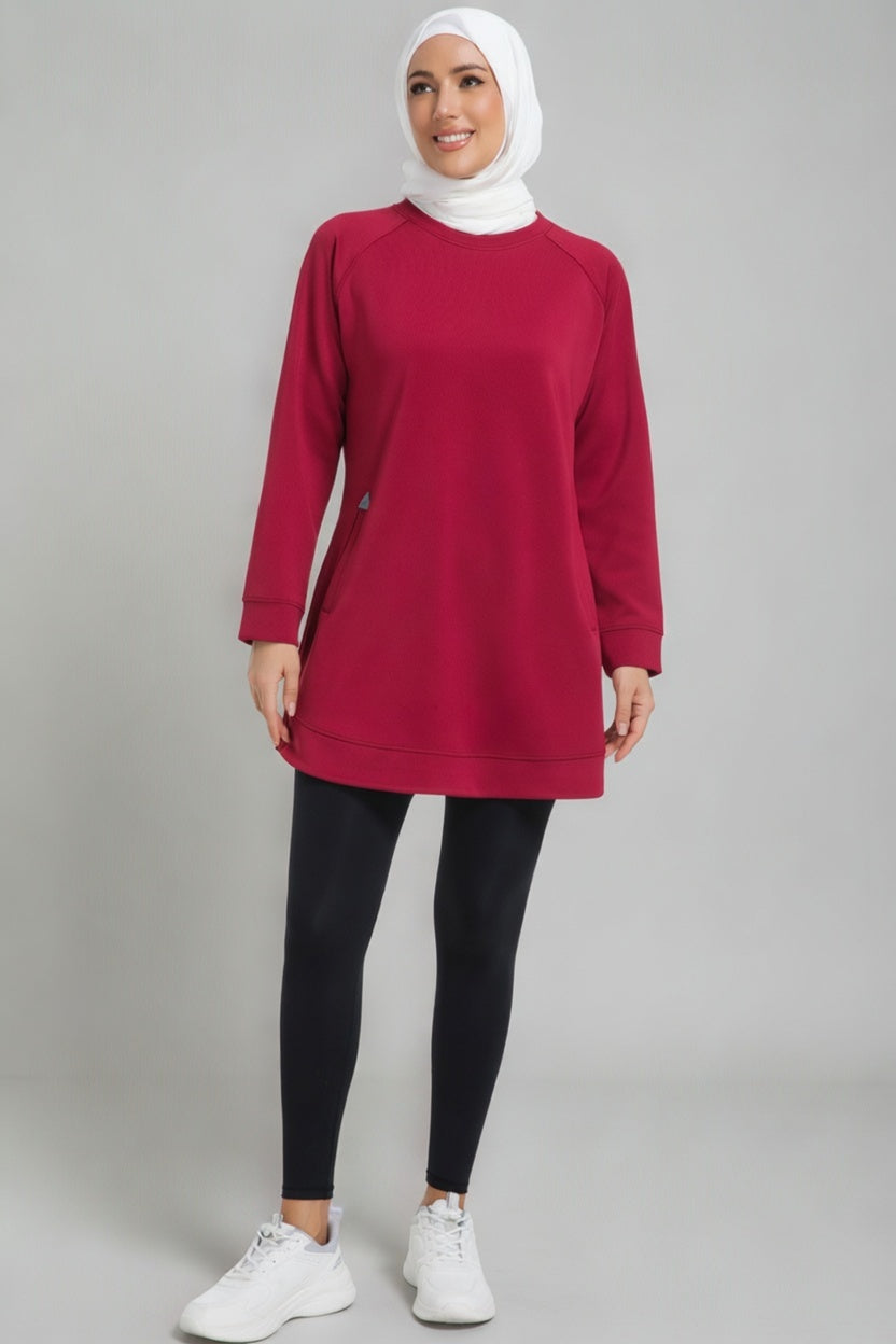 Full-length view of a female player in a maroon SVL modest padel tunic, black leggings, and white sneakers, featuring a white hijab.